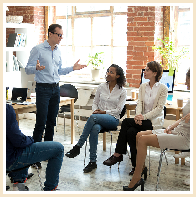 A group of people sitting in chairs and talking to each other.