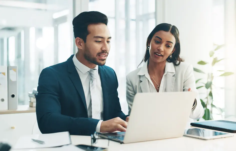 A man and woman looking at a laptop.