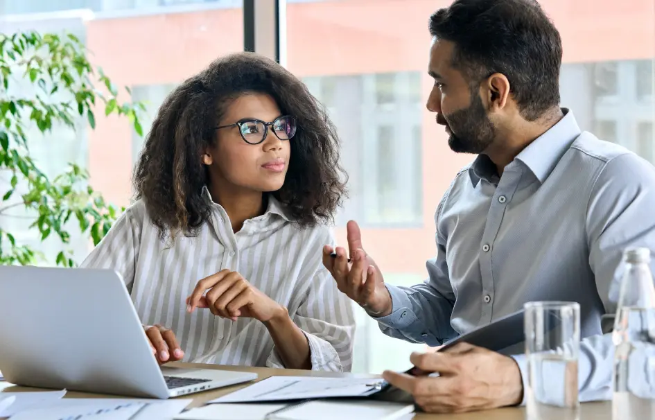 Two people sitting at a table with laptops